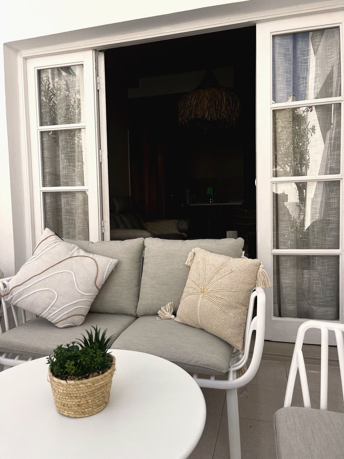 Terraza con sofá de exterior y mesa auxiliar blanca
