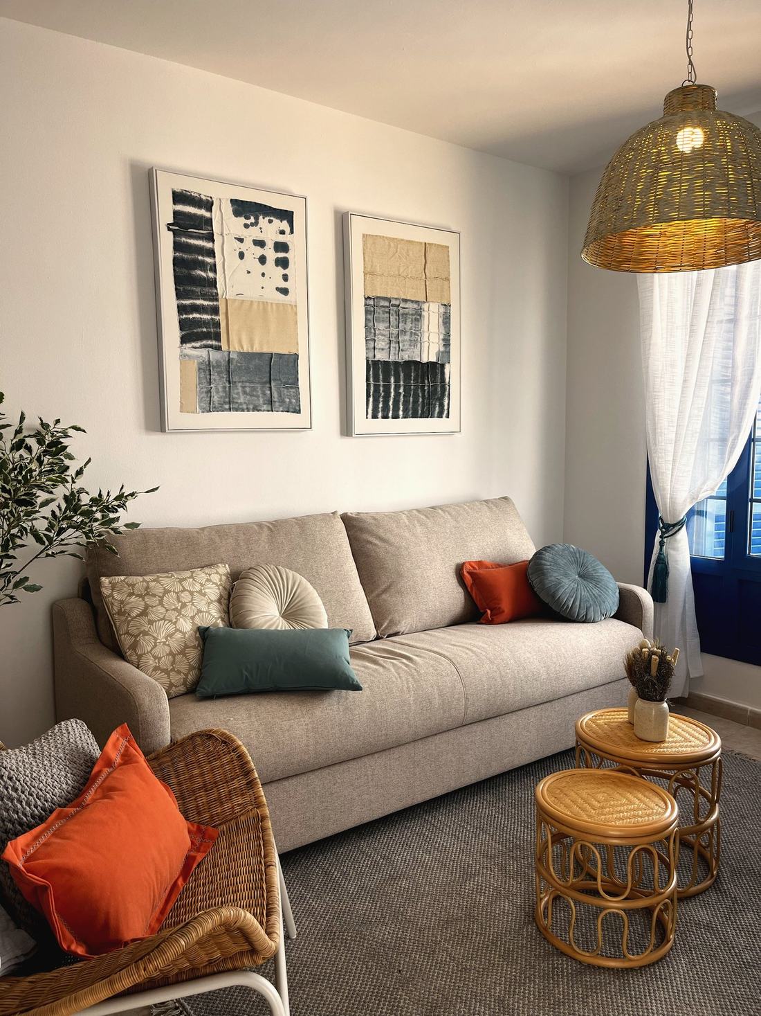 Salón con sofá, cuadros abstractos y cojines en naranja y azul