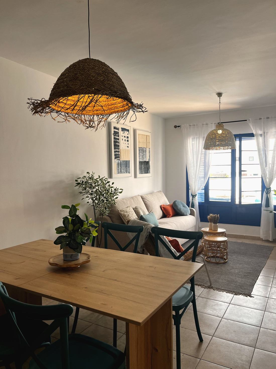 Comedor y salón con mesa de madera, sillas azul petróleo y plantas
