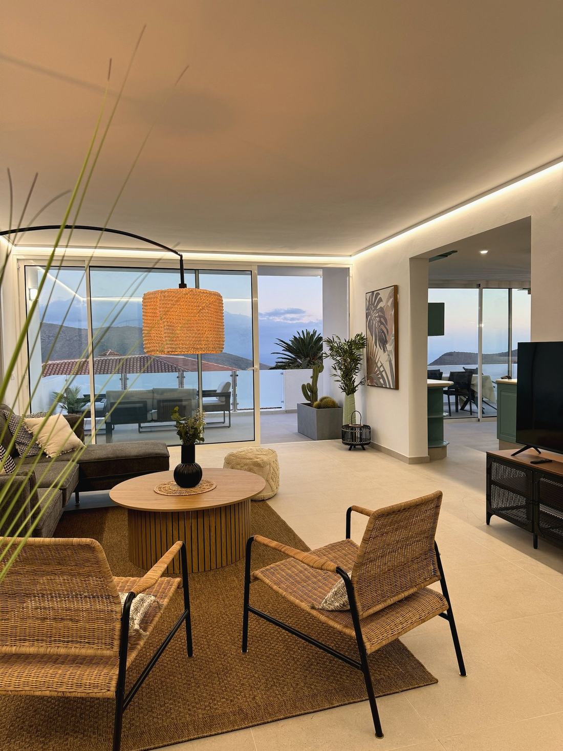 Salón con sillones de ratán, mesa de centro y vistas a la terraza