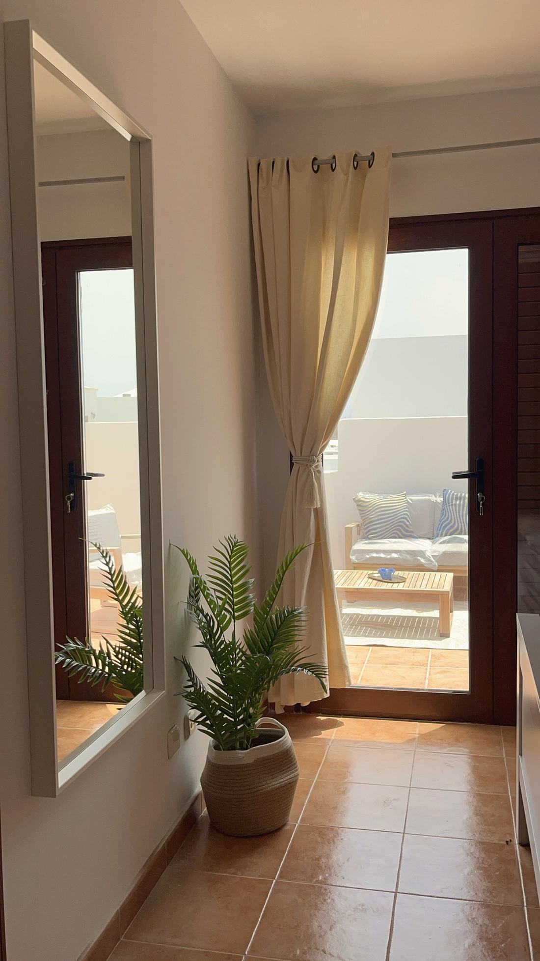 Pasillo con espejo, planta y puerta a la terraza de una vivienda vacacional