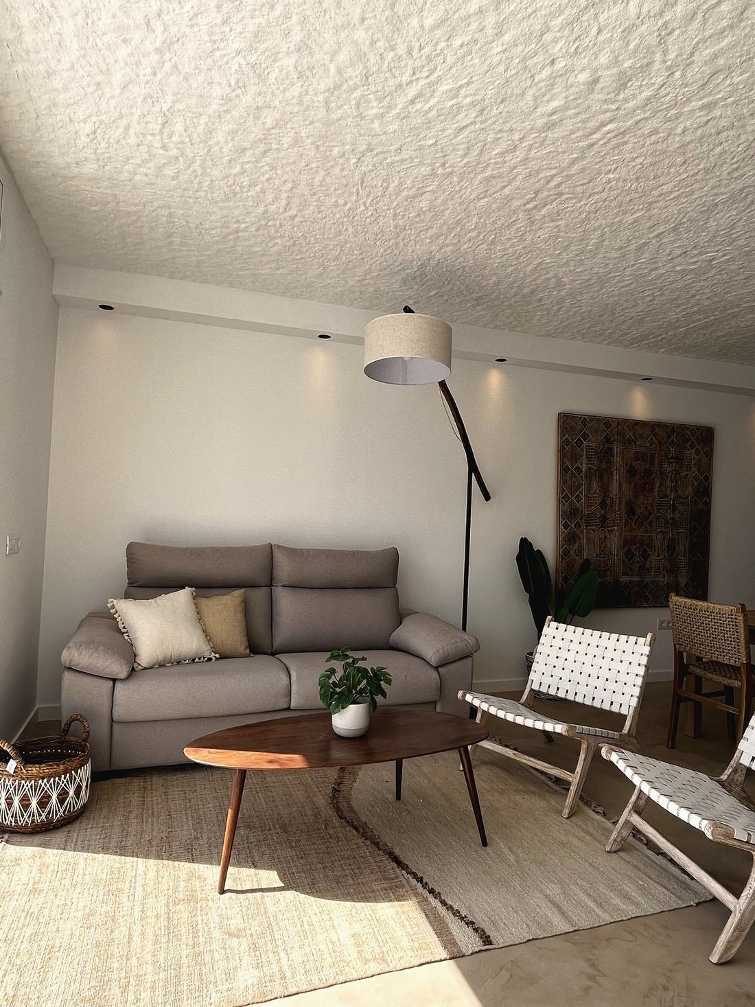 Salón con sofá gris, mesa de centro de madera y sillones de fibra blanca