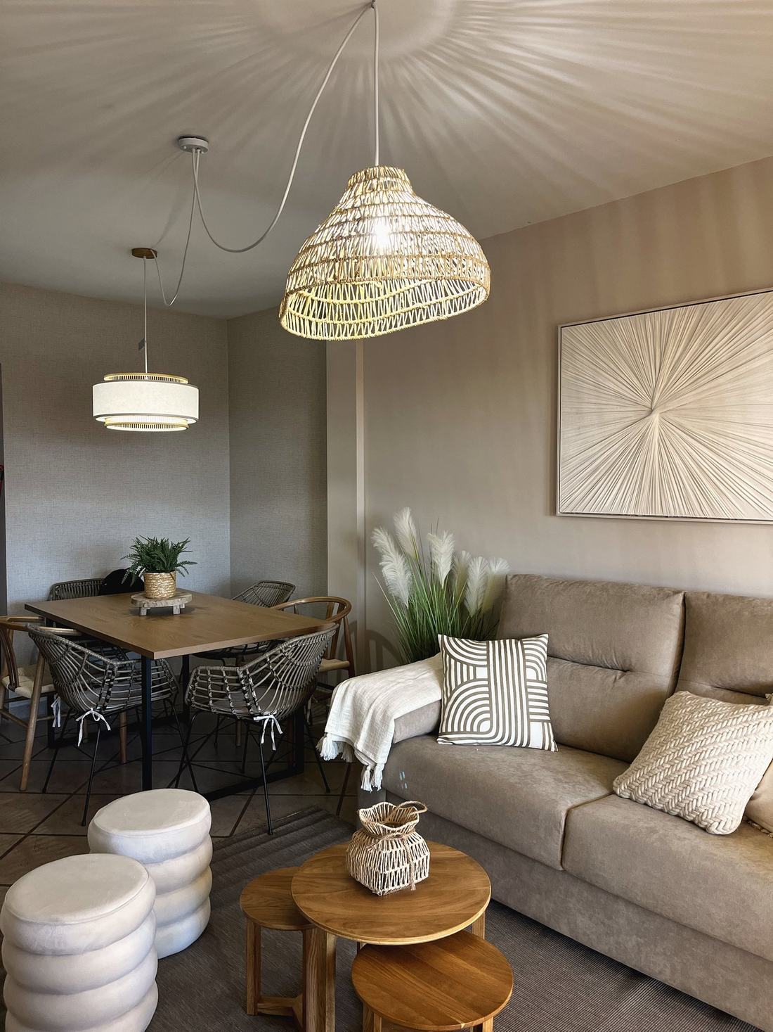 Salón comedor con lámparas de mimbre, sofá y mesas nido de madera