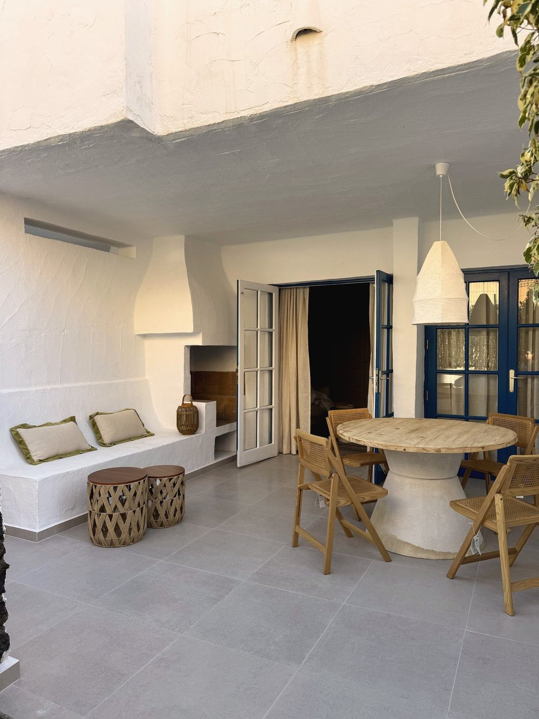 Terraza con banco de obra, mesa redonda de madera y sillas plegables de rejilla