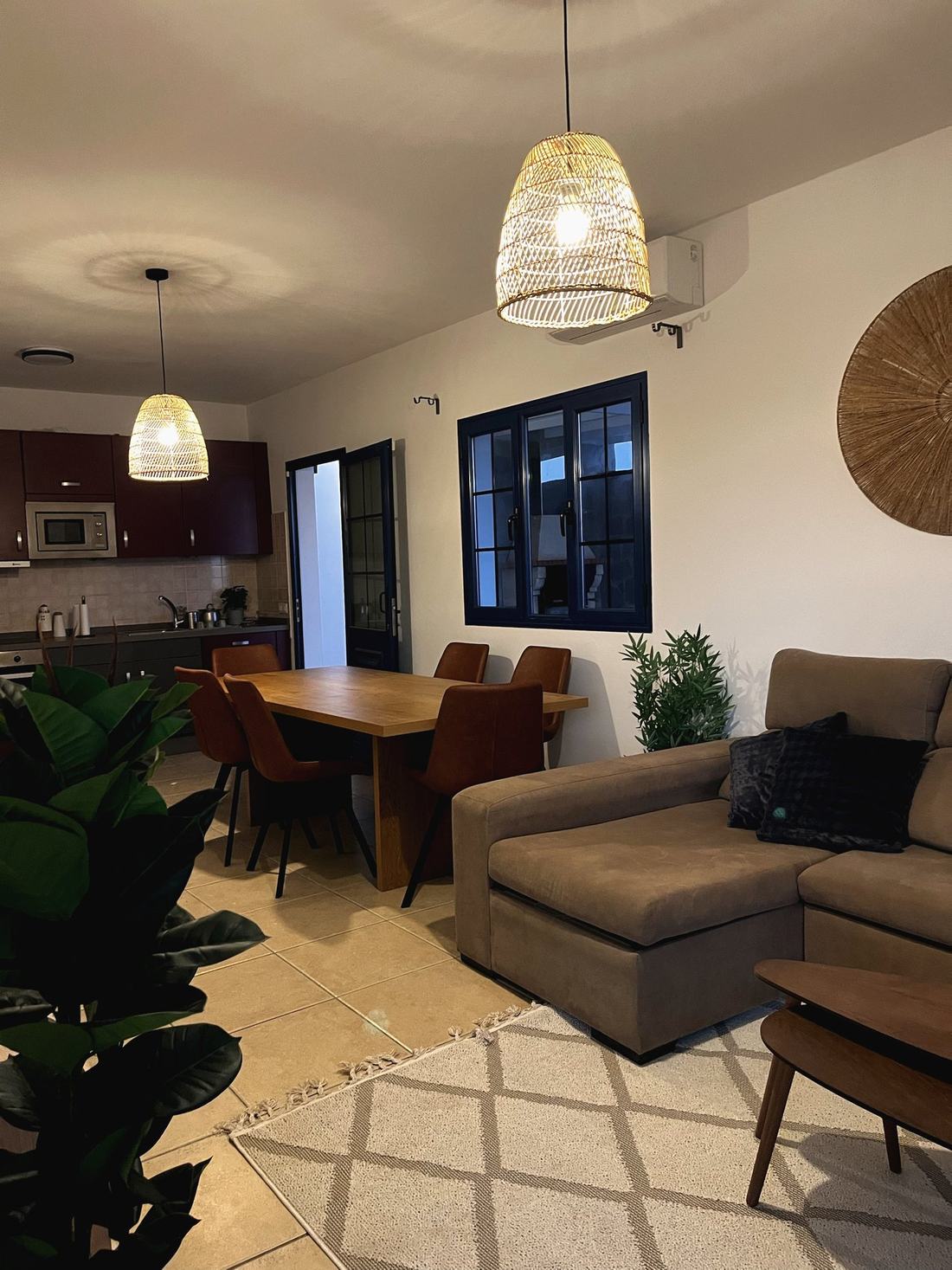 Salón comedor con mesa de madera, sillas de cuero marrón y sofá en tonos tierra