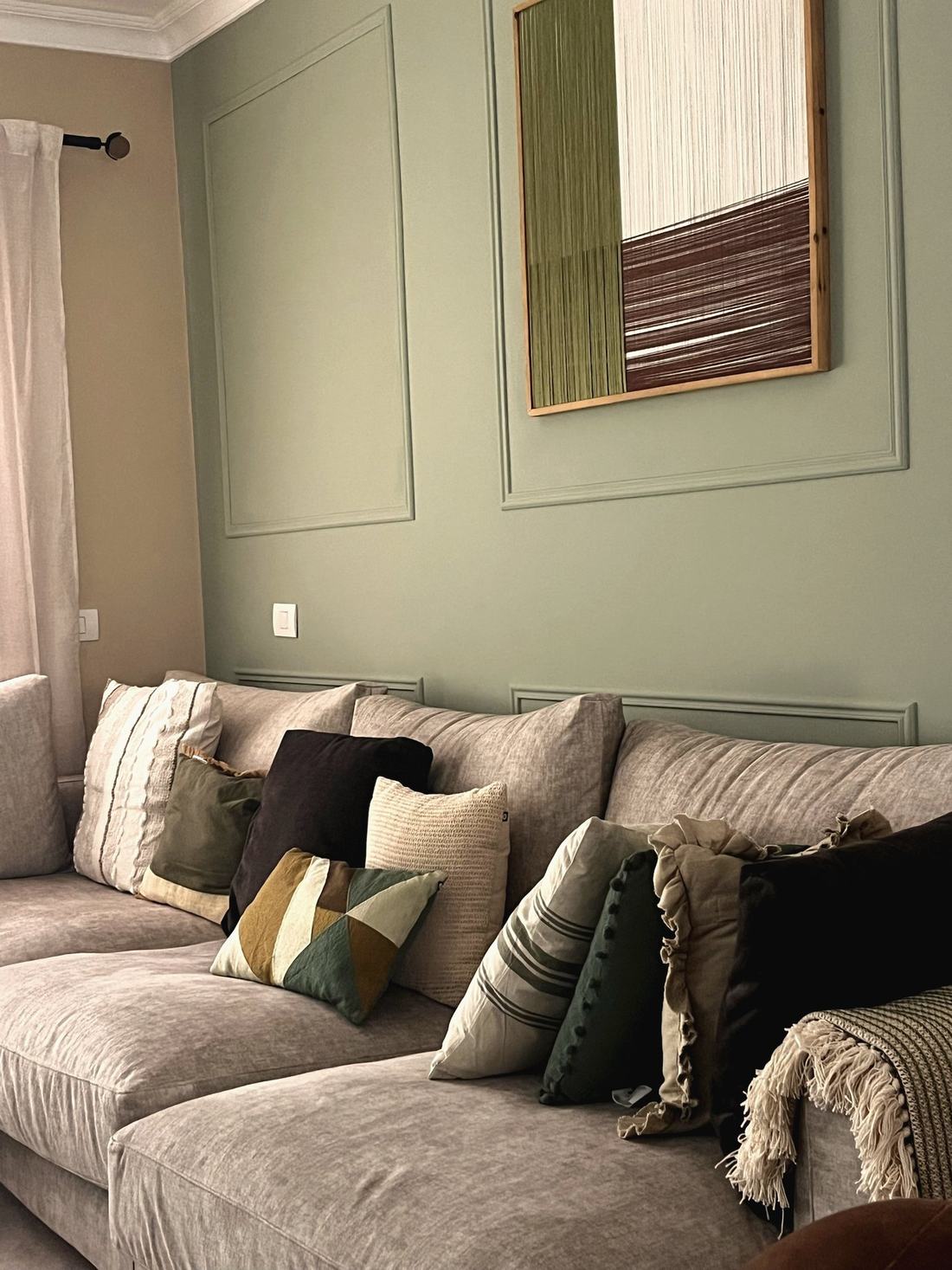 Detalle del sofá con cojines en verde, negro y beige