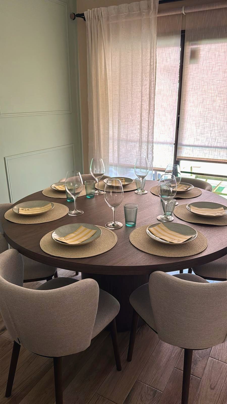 Mesa redonda puesta para una cena, con mantelería y copas