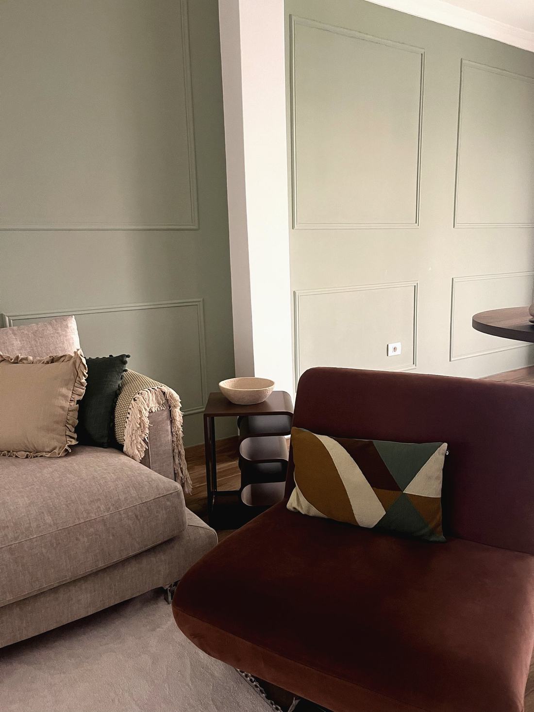 Rincón del salón con sillón terracota, cojín geométrico y mesa auxiliar negra